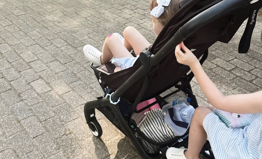 Parent pushing stroller with secure silicone phone holder mounted on handlebar, demonstrating vibration-free map viewing