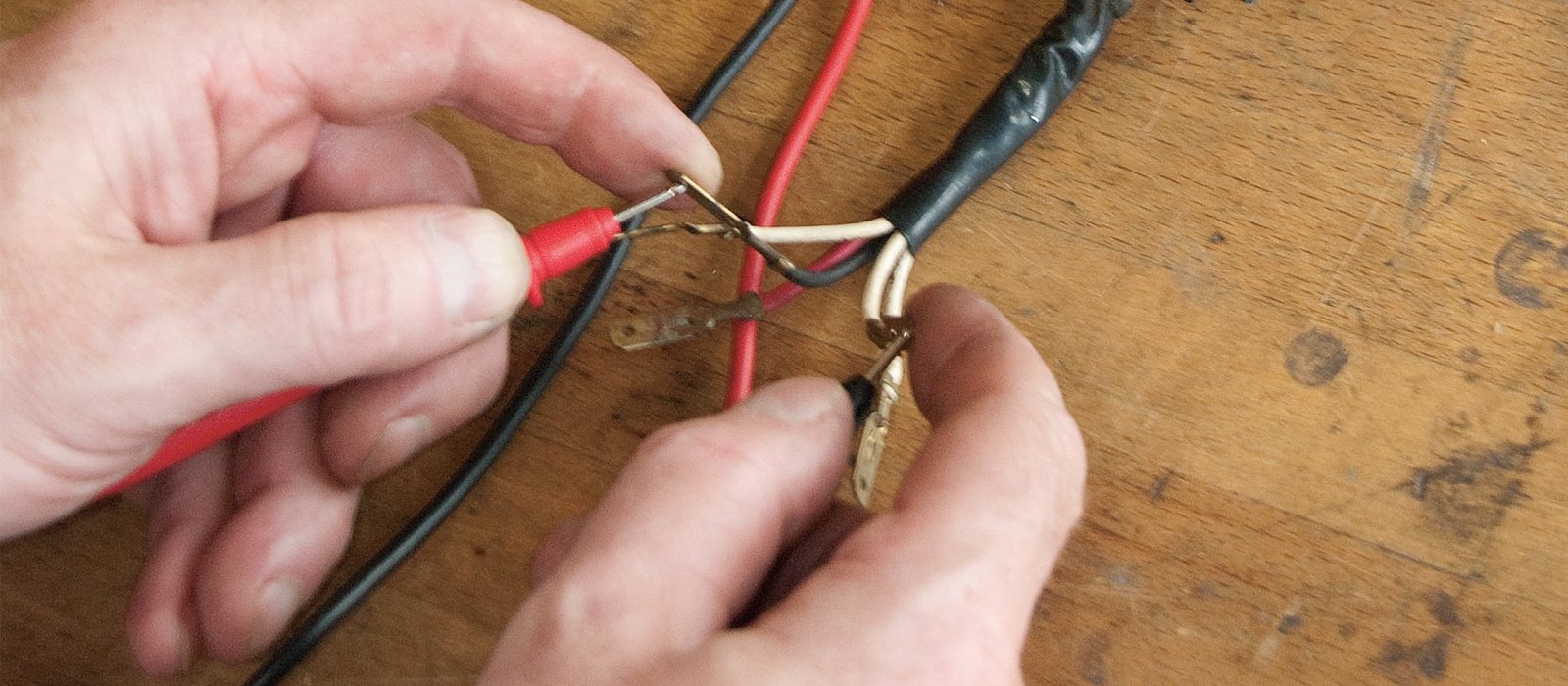 Multimeter probes testing a brushless motor's phase wires on a workbench, with motor and multimeter visible